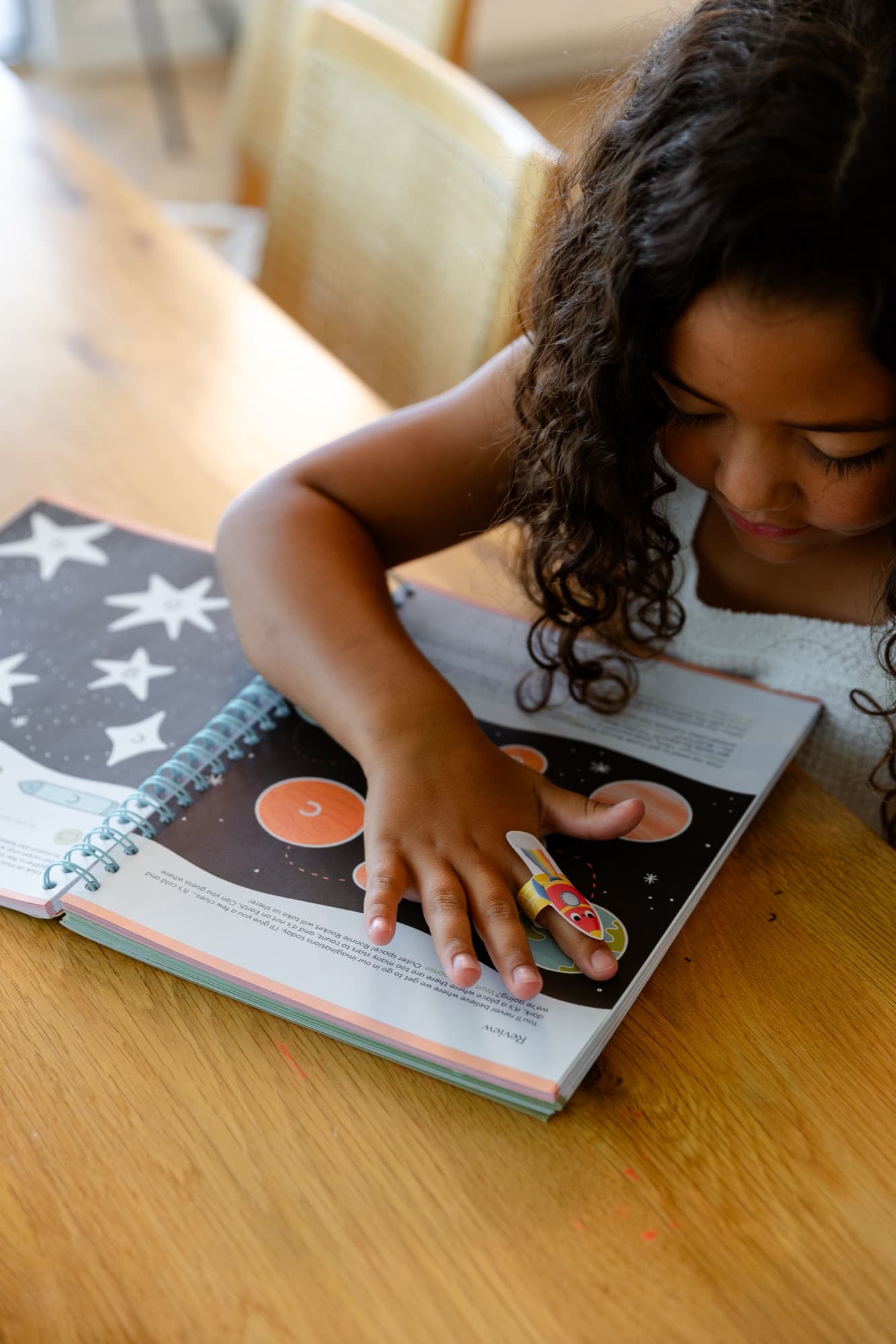 A child flying the rocket finger puppet through a lesson page
